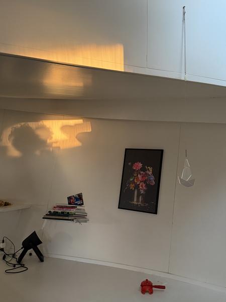 This photo captures a minimalist room interior, bathed in the warm glow of golden hour sunlight reflecting on the white walls